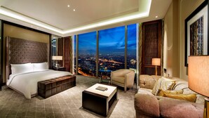 A modern hotel room with a large bed, a seating area, and a city view through floor-to-ceiling windows. - Hilton Istanbul Bomonti Hotel & Conference Center (Istanbul)