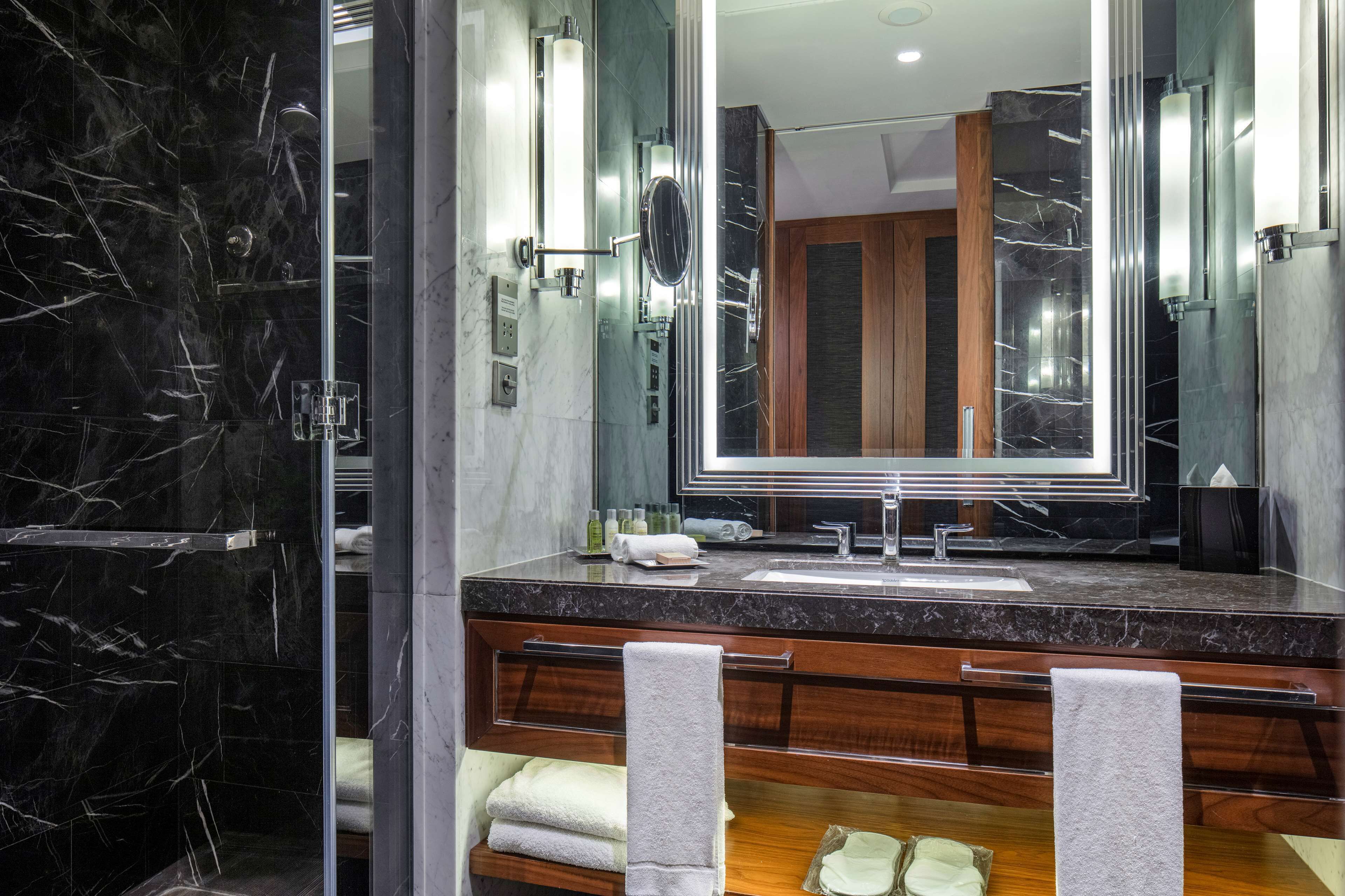 A modern bathroom with a marble vanity, a large mirror, and a shower area.