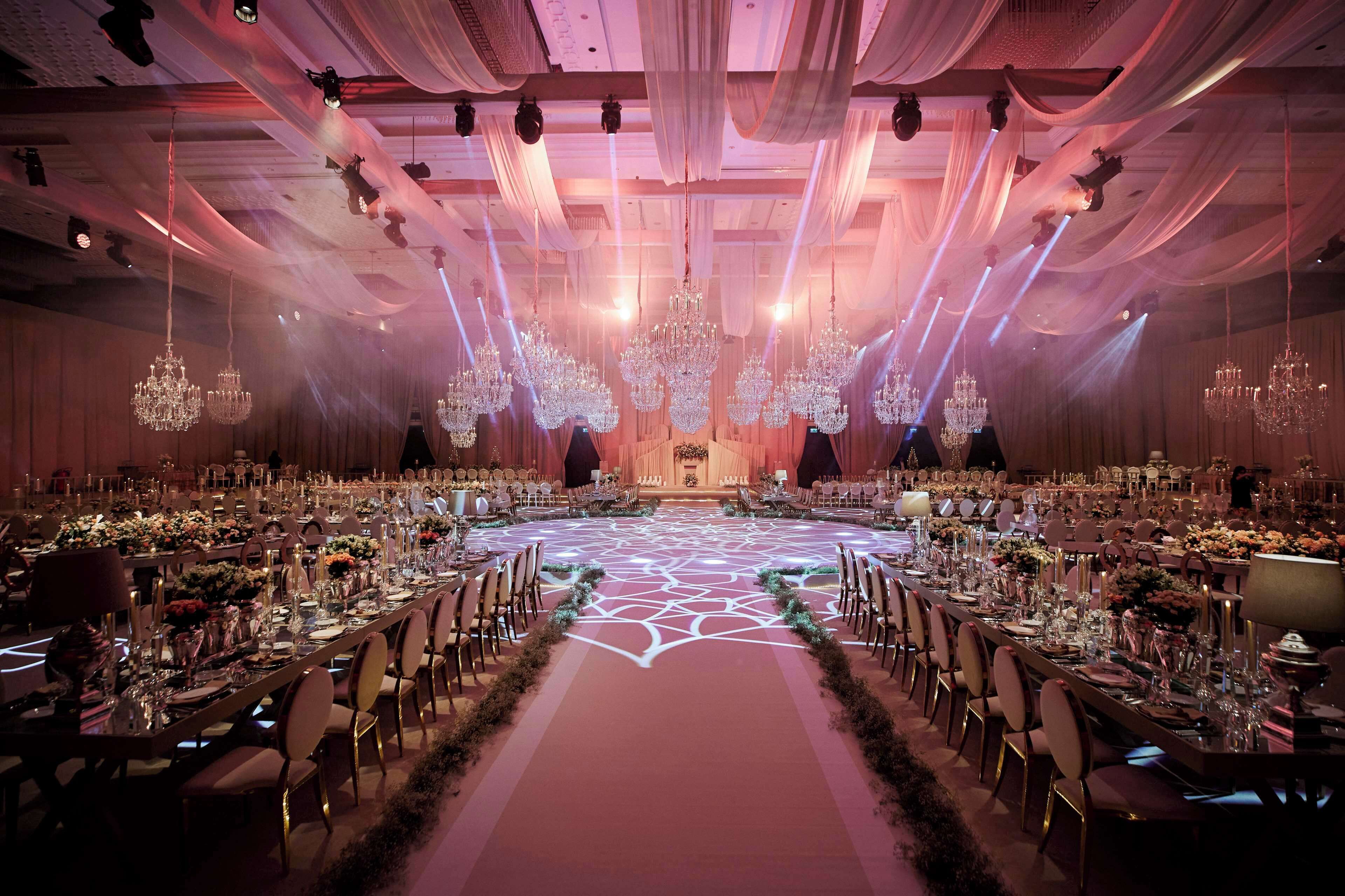 Un salón de banquetes con mesas redondas, candelabros y cortinas drapeadas.