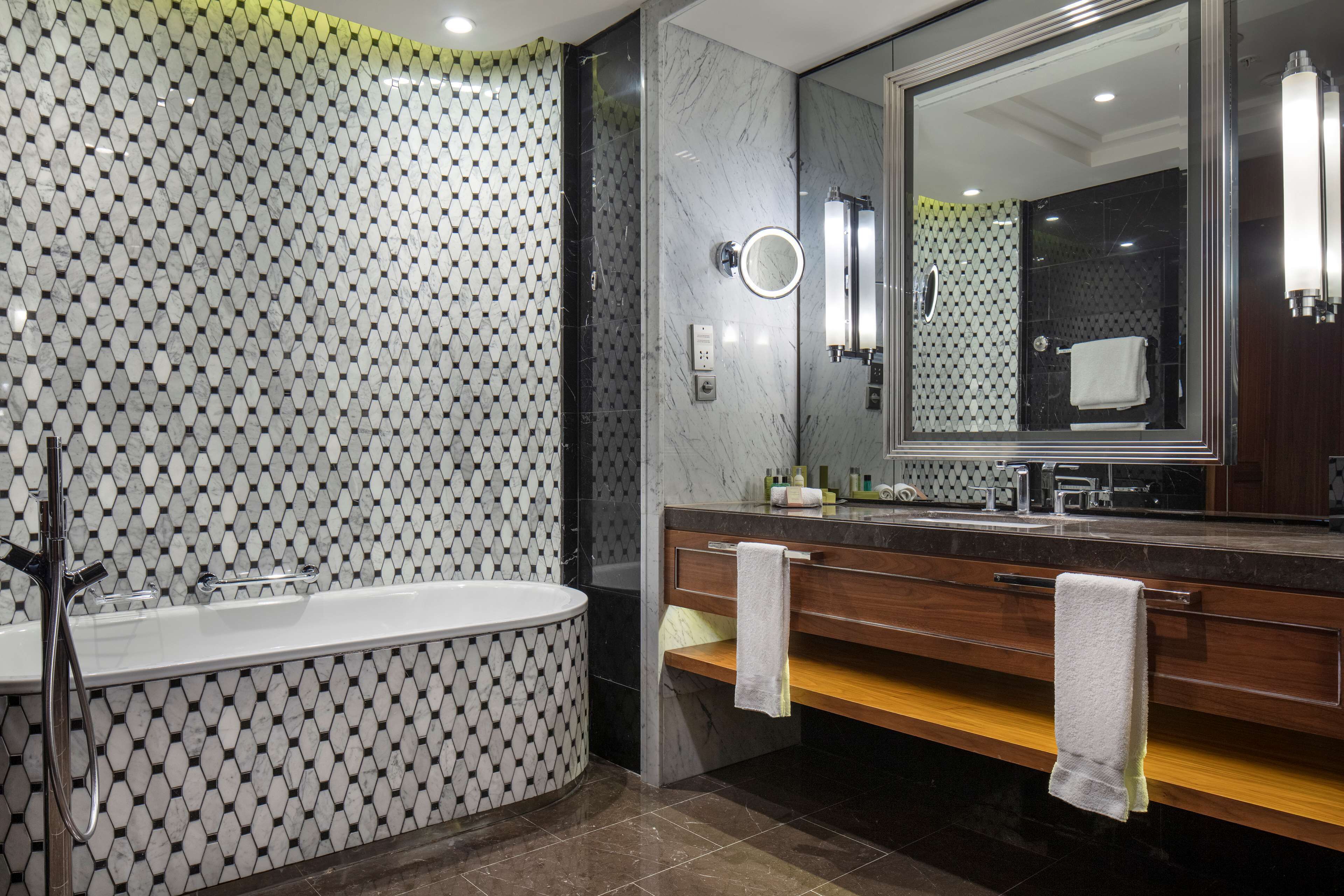 A modern bathroom with a freestanding bathtub, a large mirror, and a vanity with a towel rack.