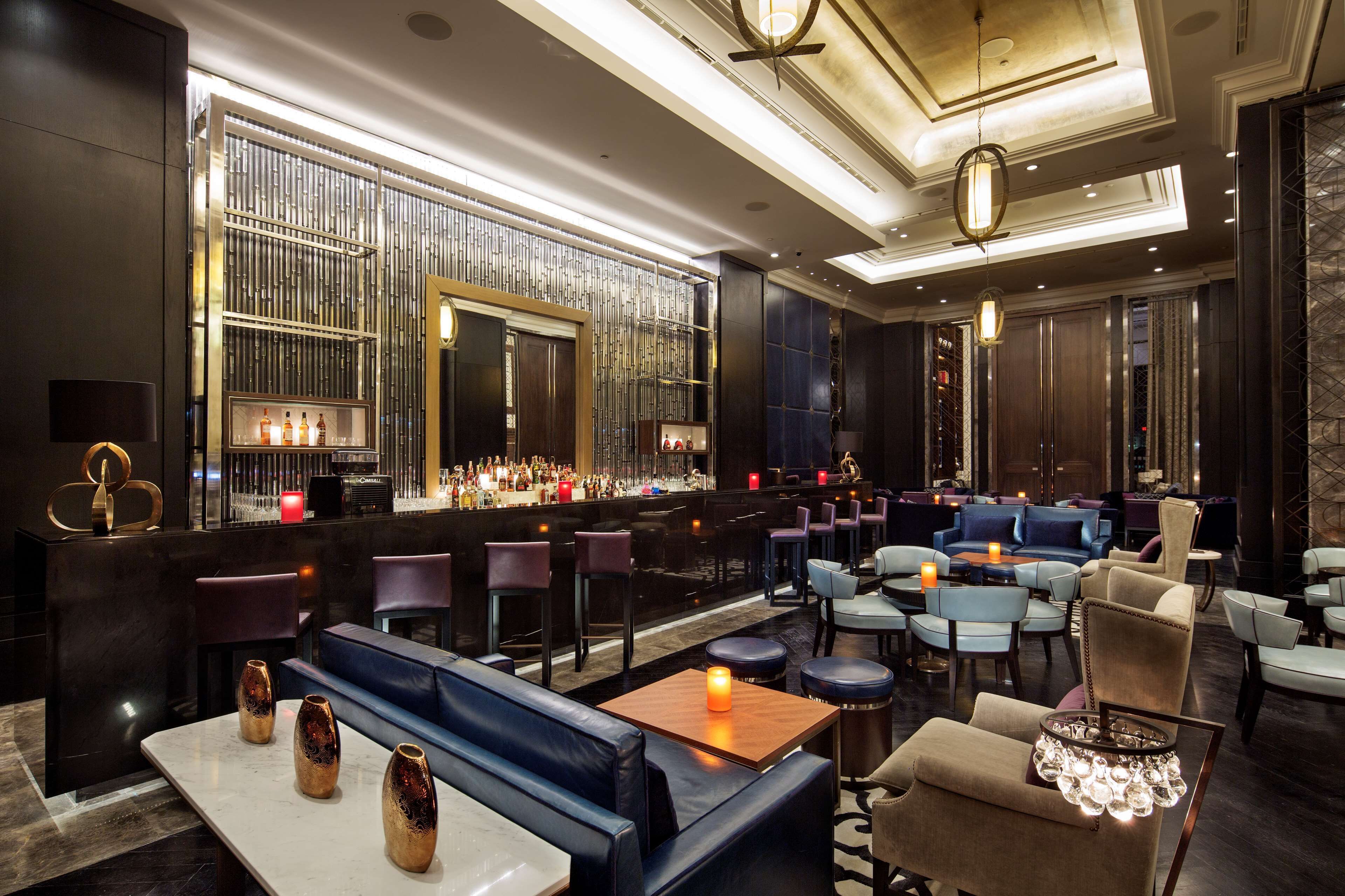 A modern bar area with seating, a bar counter, and decorative lighting.