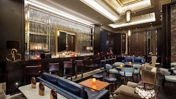 A modern bar area with seating, a bar counter, and decorative lighting.