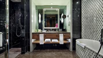 A modern bathroom with a large mirror, a bathtub, and a shower area.