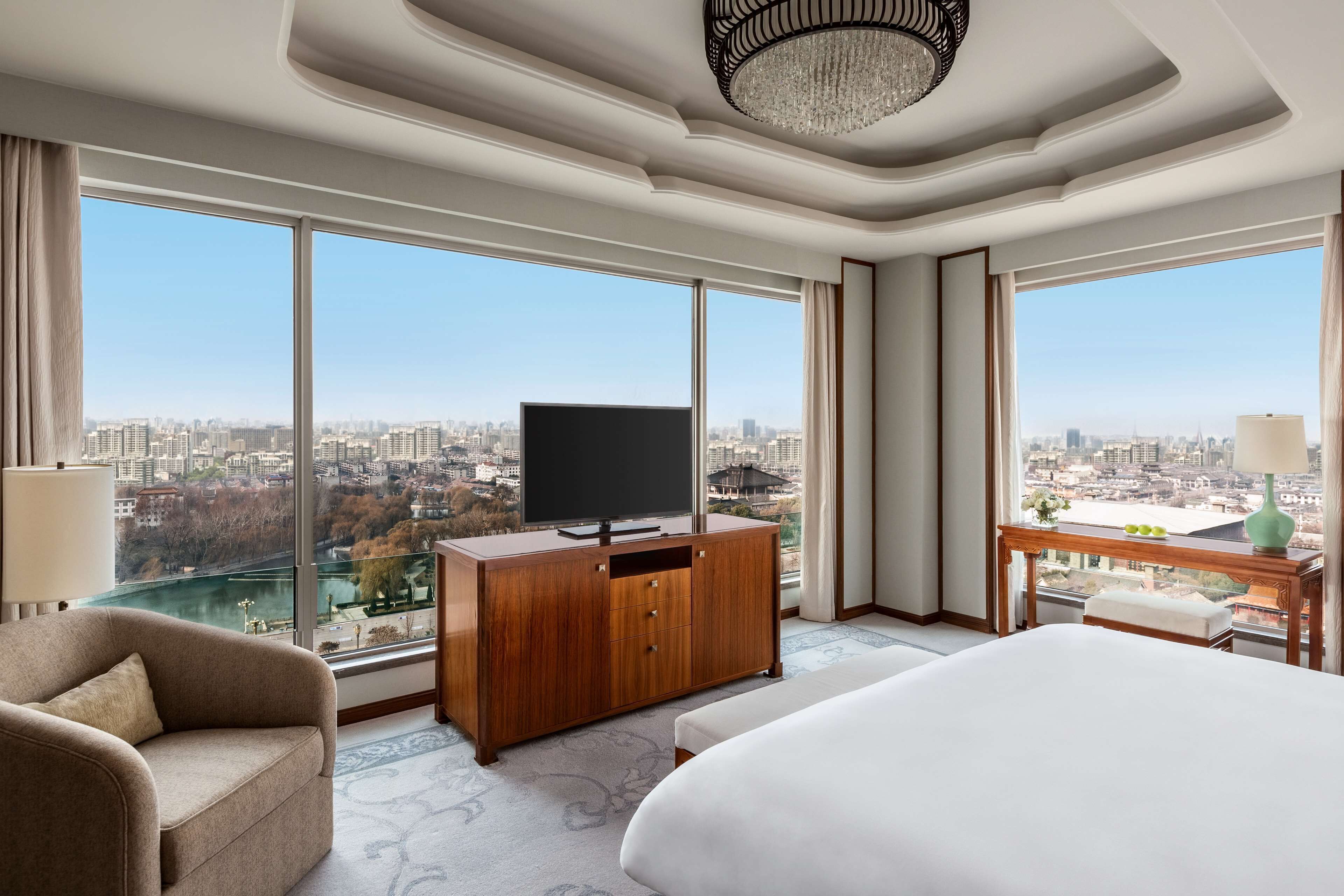 Una habitación de hotel moderna con una cama grande, un televisor sobre un mueble de madera y un escritorio con una lámpara.