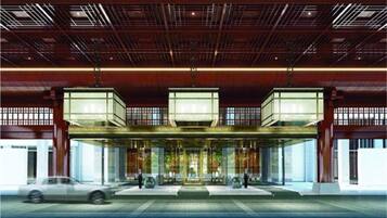 Un edificio moderno con una entrada amplia, múltiples puertas de cristal y un techo de estructura metálica.