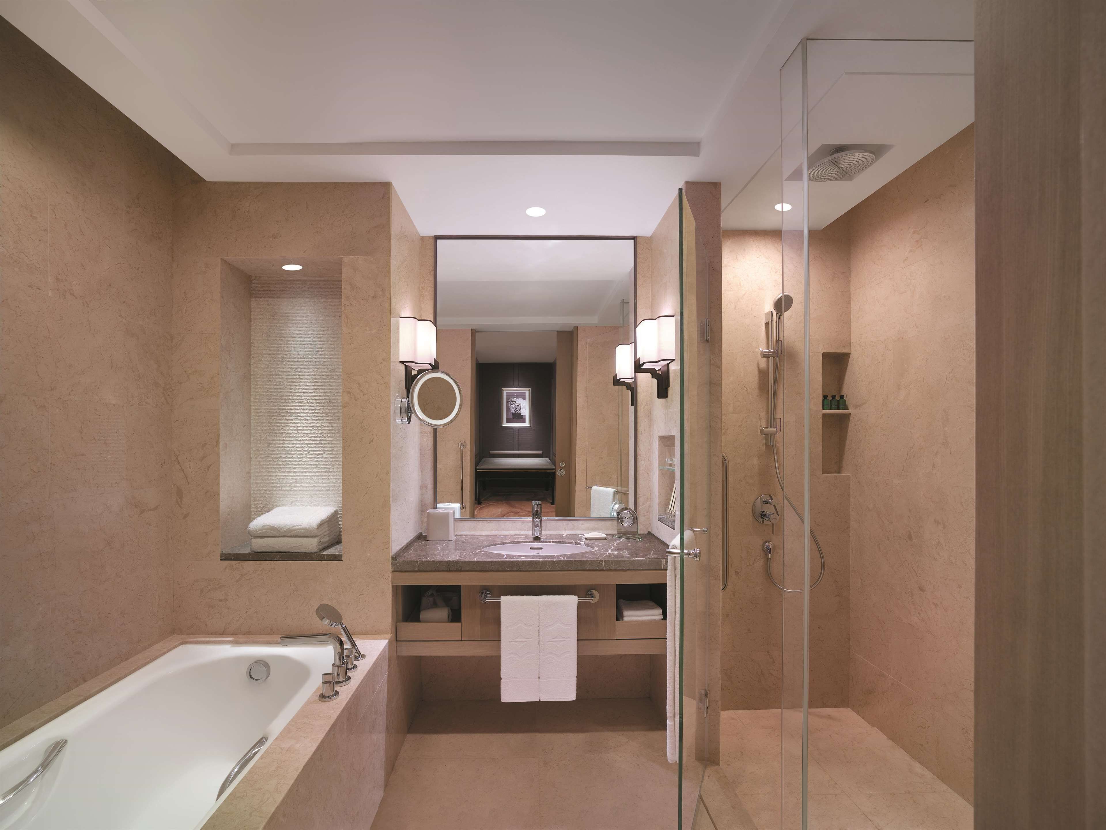 A modern bathroom with a bathtub, a sink with a mirror, and a glass-enclosed shower.