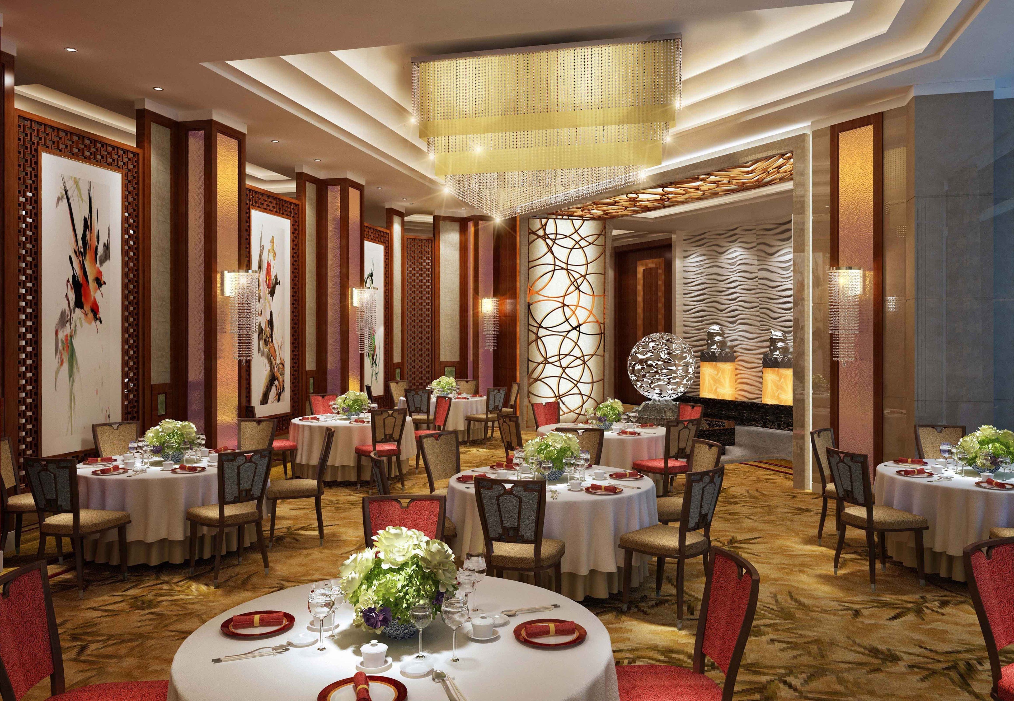 A hotel dining area with round tables, chairs, and a chandelier.