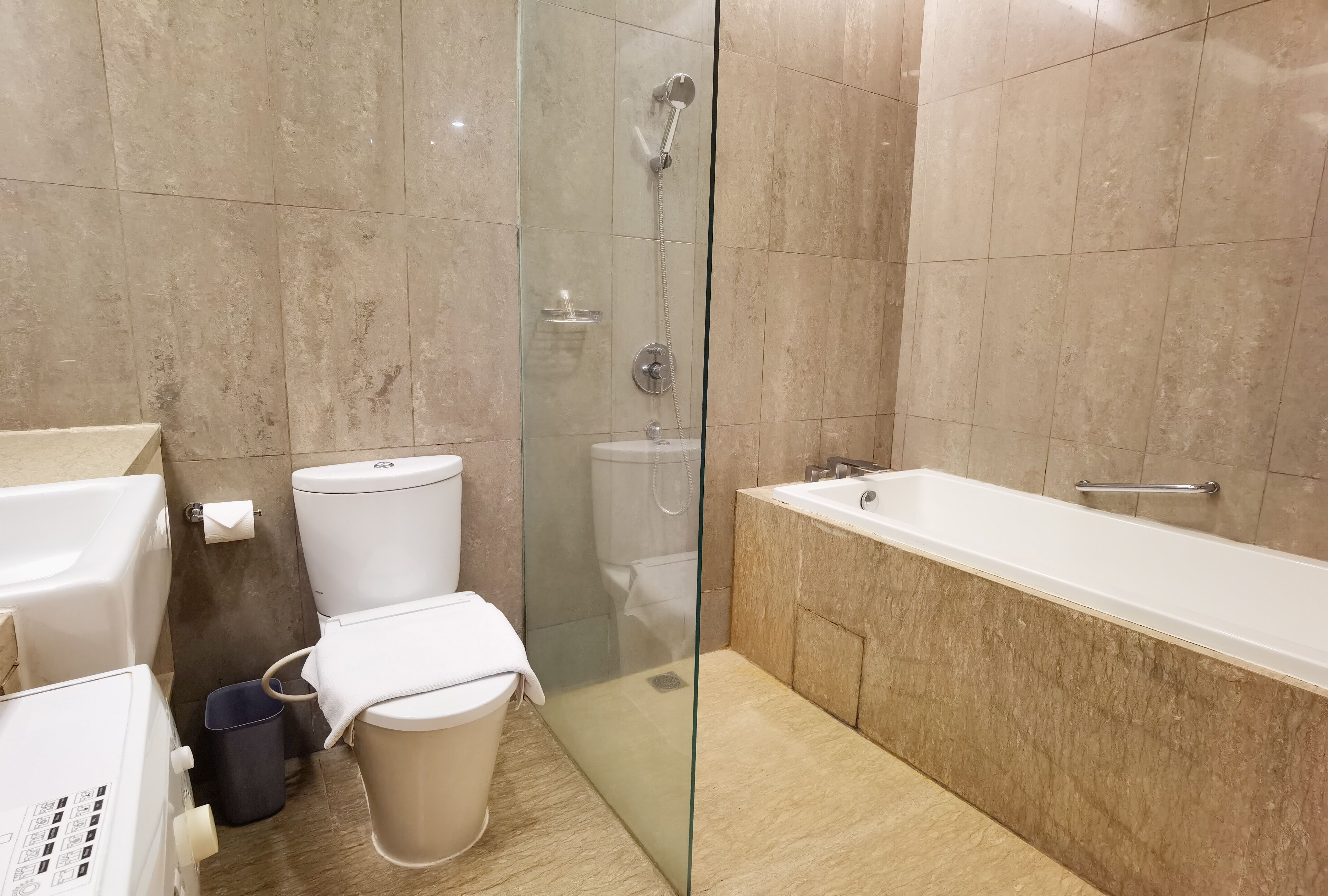 Un baño moderno con ducha de mampara de vidrio, bañera y retrete.
