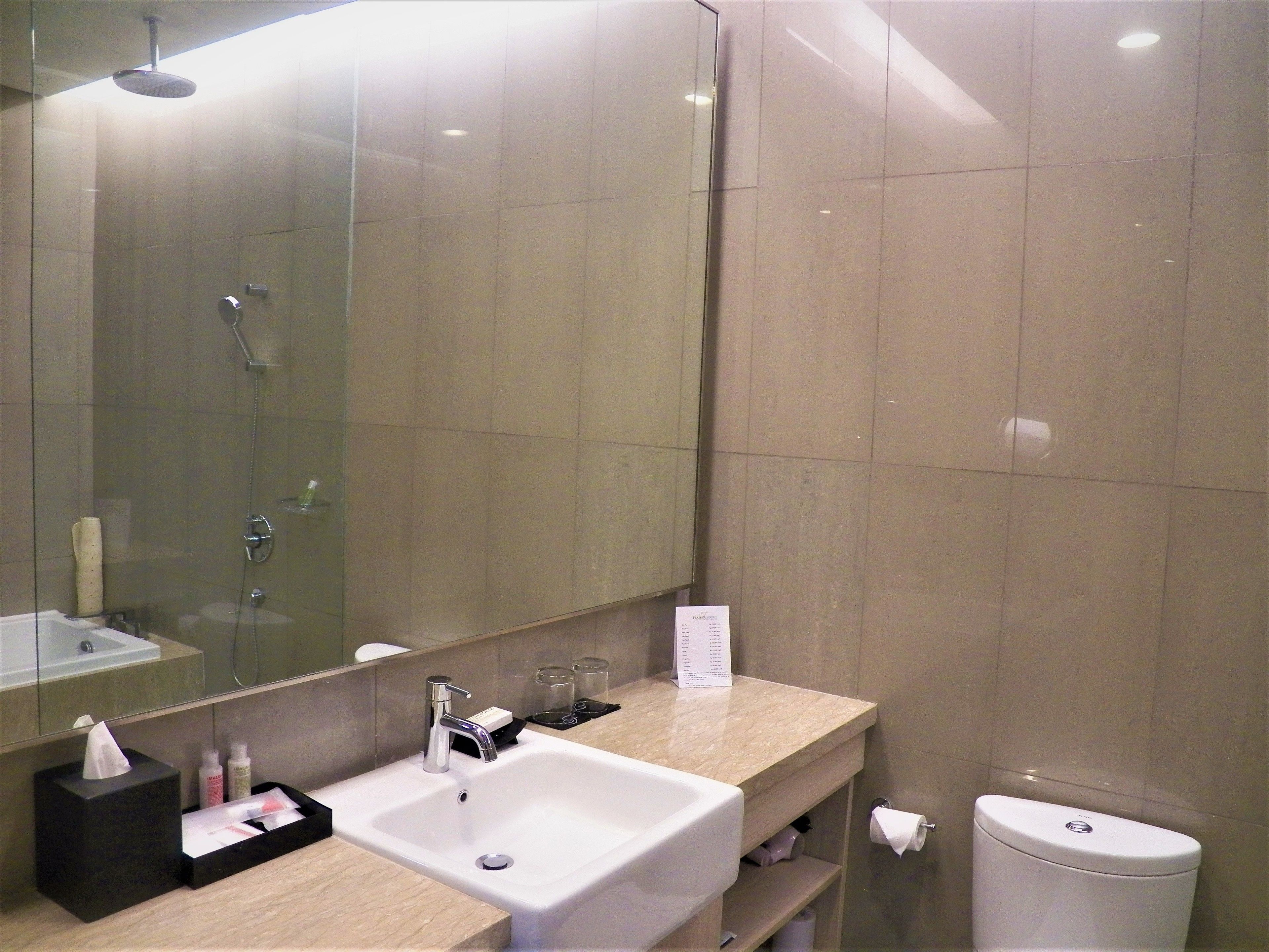 A modern bathroom with a large mirror, a sink, and a toilet.
