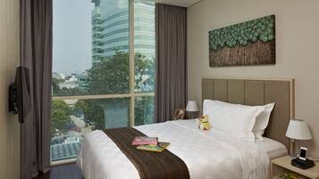 A hotel room with a large window, a bed with a white and brown striped bedspread, a nightstand with a lamp, and a wall-mounted artwork.