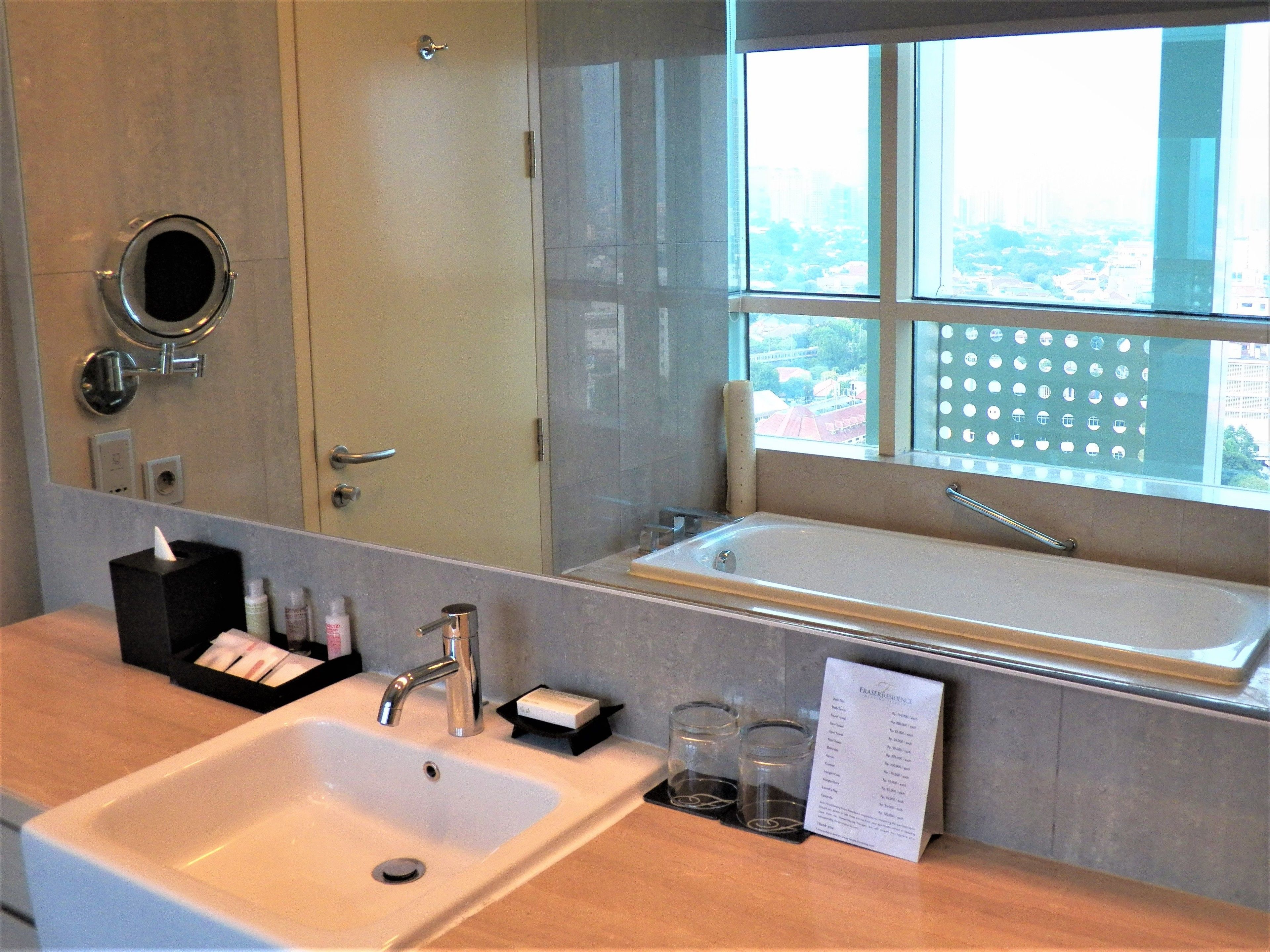 A modern bathroom with a large mirror, a sink, and a bathtub.