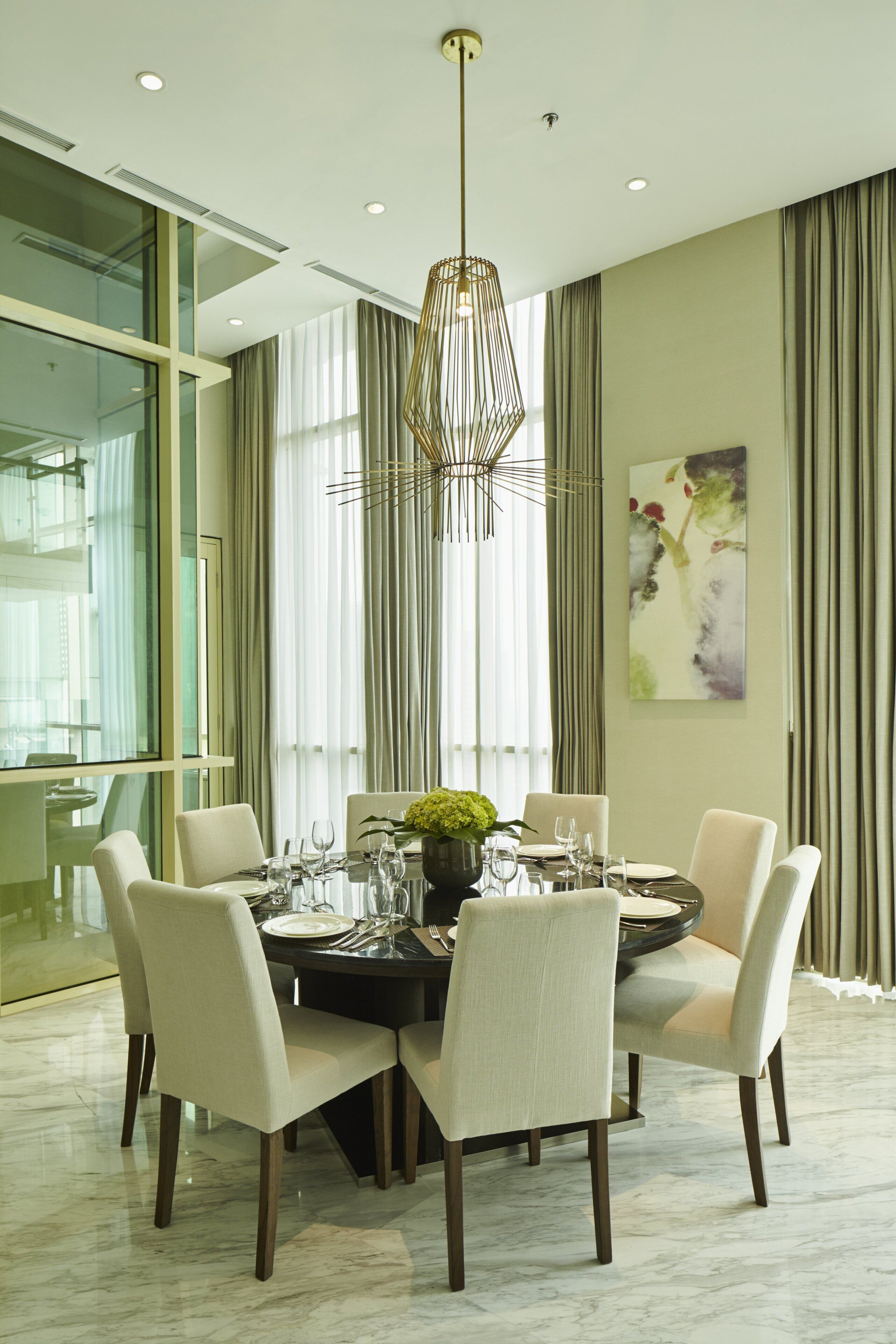 A modern dining area with a round table, six chairs, and a chandelier.