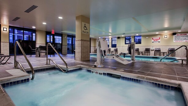 A hotel pool area with a pool lift, seating area, and pool regulations sign. - Hilton Garden Inn Lincoln Downtown/Haymarket (Lincoln)