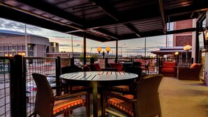 An outdoor seating area with wicker chairs and a round table, overlooking a cityscape. - Hilton Garden Inn Lincoln Downtown/Haymarket (Lincoln)