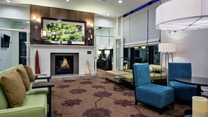 A modern hotel lobby with a fireplace, comfortable seating, and a large TV screen. - Hilton Garden Inn Lincoln Downtown/Haymarket (Lincoln)