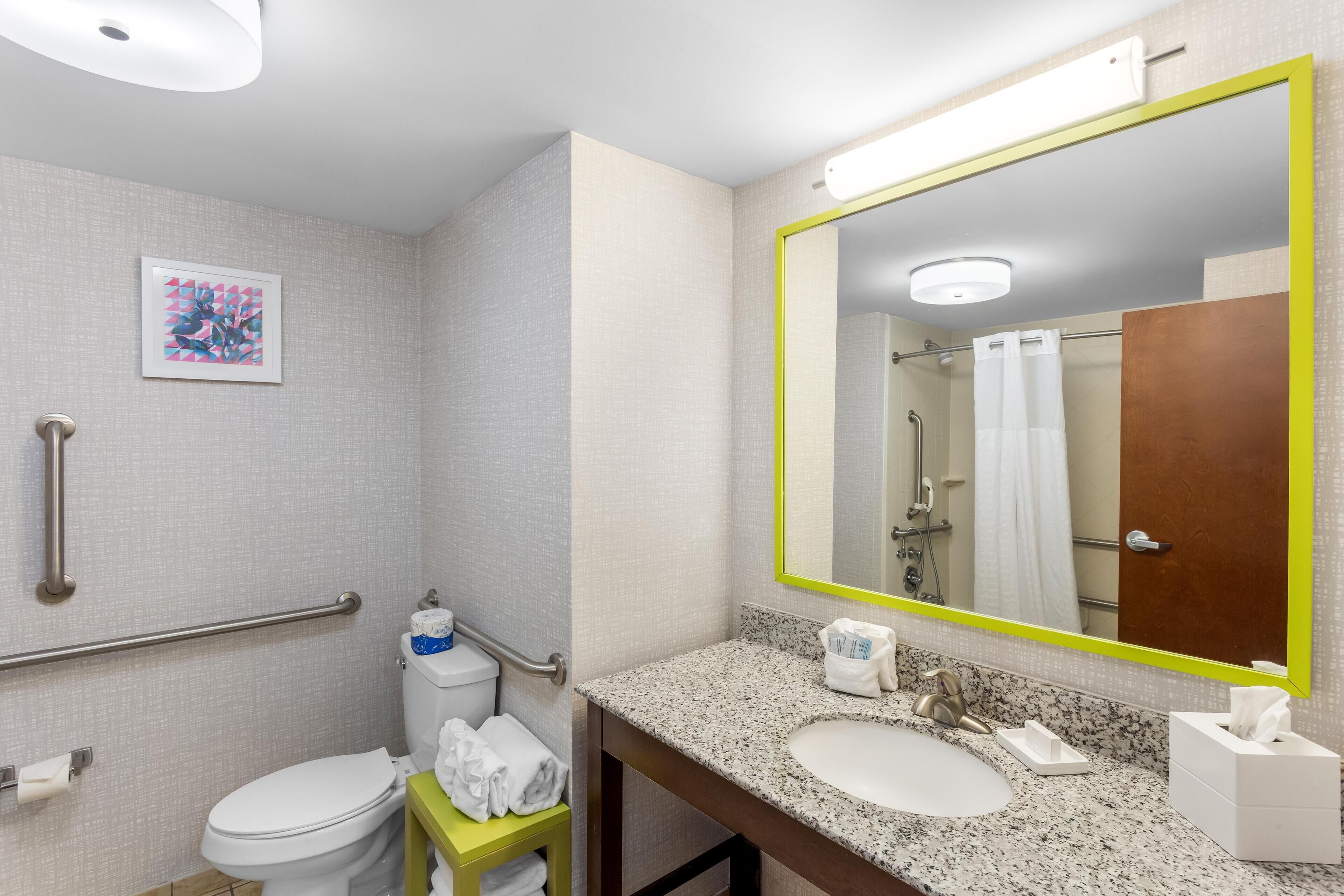 A bathroom with a white toilet, a sink with a mirror, and a towel rack.