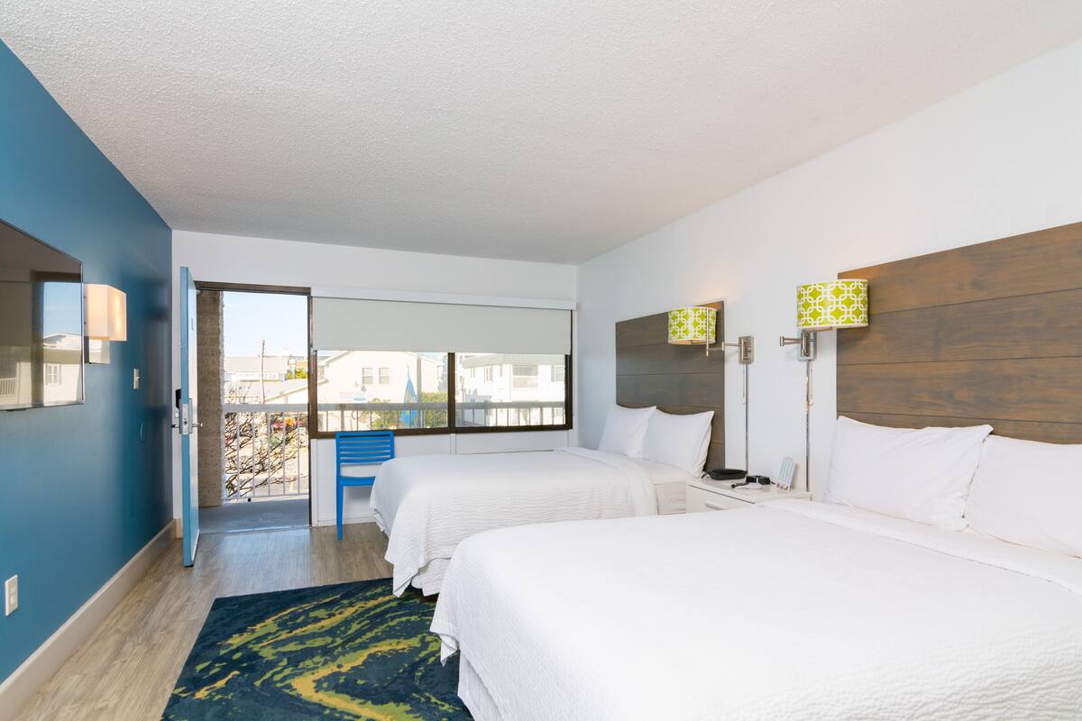 A hotel room with two beds, a large window, and a view of the city.