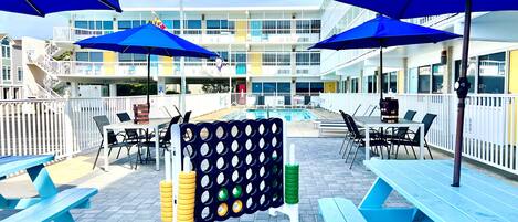 A poolside area with blue umbrellas, picnic tables, and a pool.