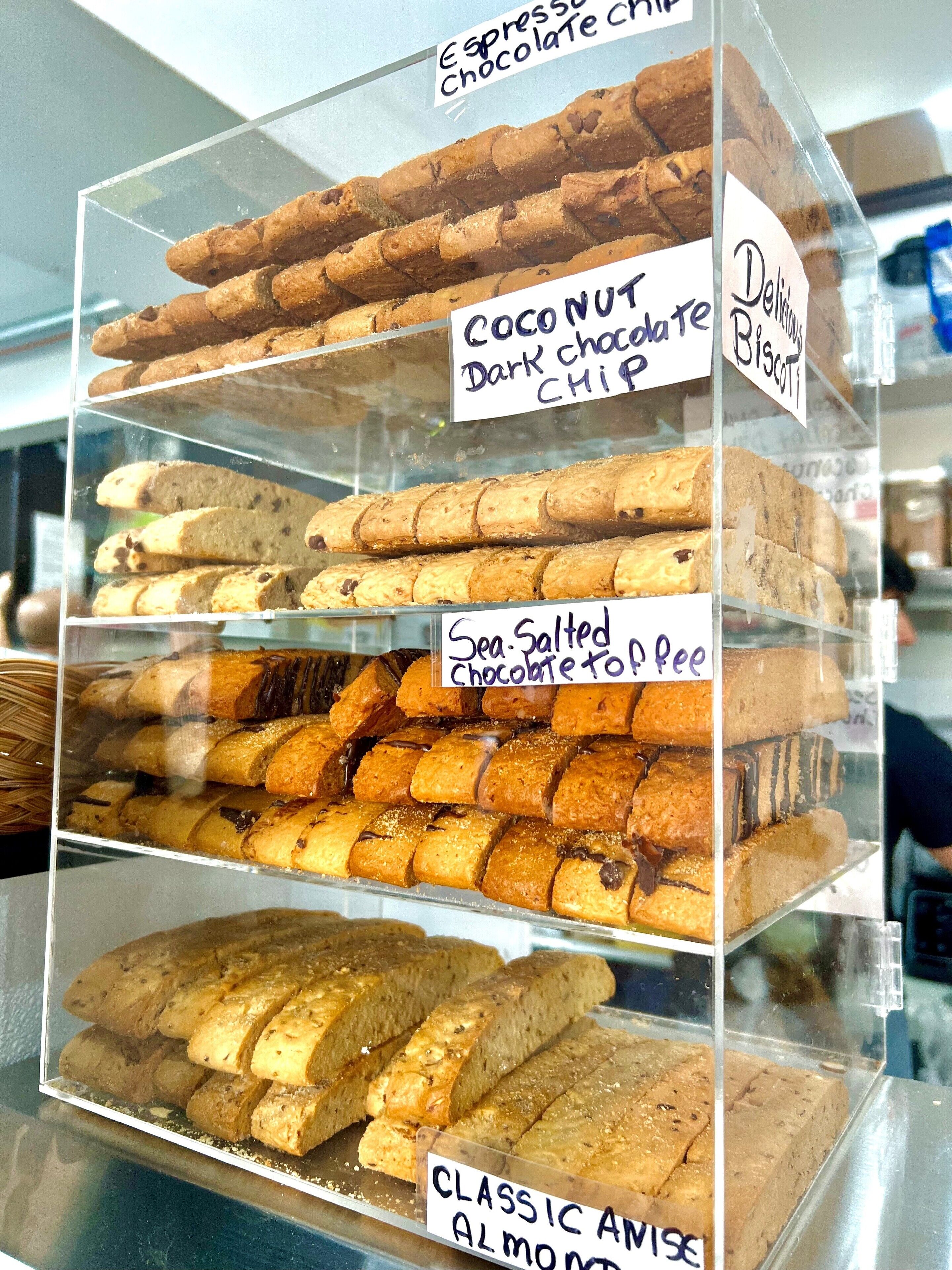 Vitrine com diversos produtos de panificação, incluindo bolachas de chocolate, bolachas de chocolate amargo e coco, bolachas de caramelo com chocolate e flor de sal, e biscoitos de amêndoa clássicos.