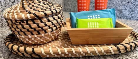 A woven basket and a wooden tray with colorful bags on a kitchen counter.
