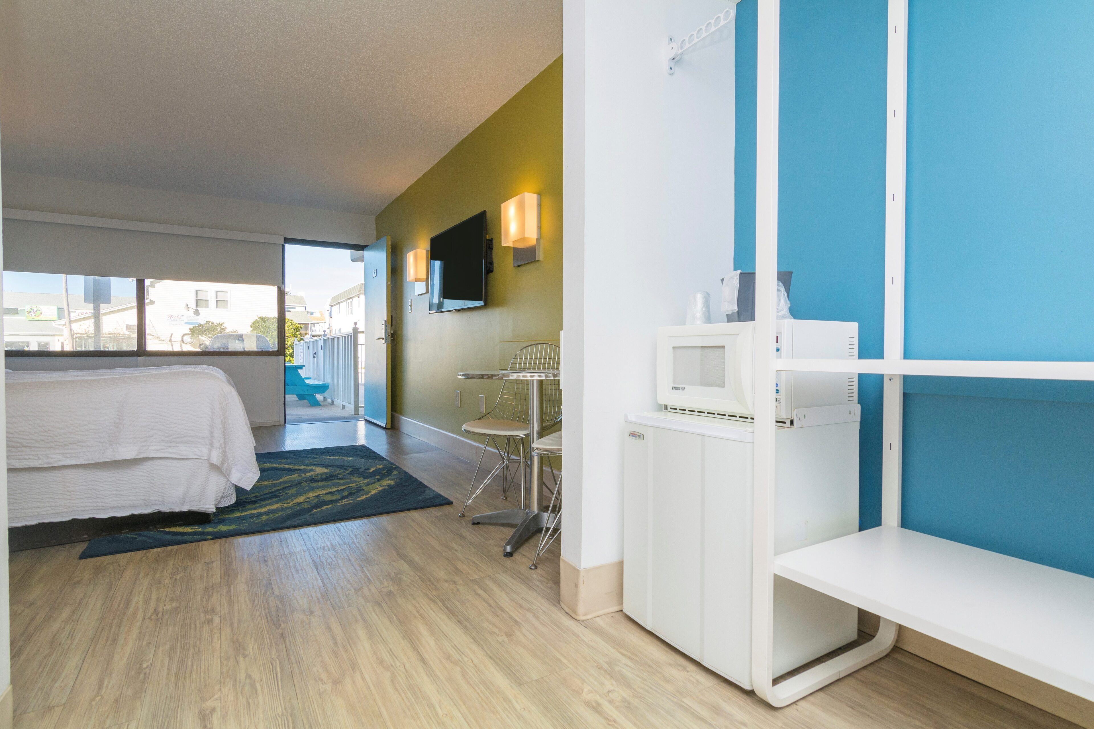 Habitación de hotel con cama, escritorio, silla, televisor y ventana con vista al exterior.