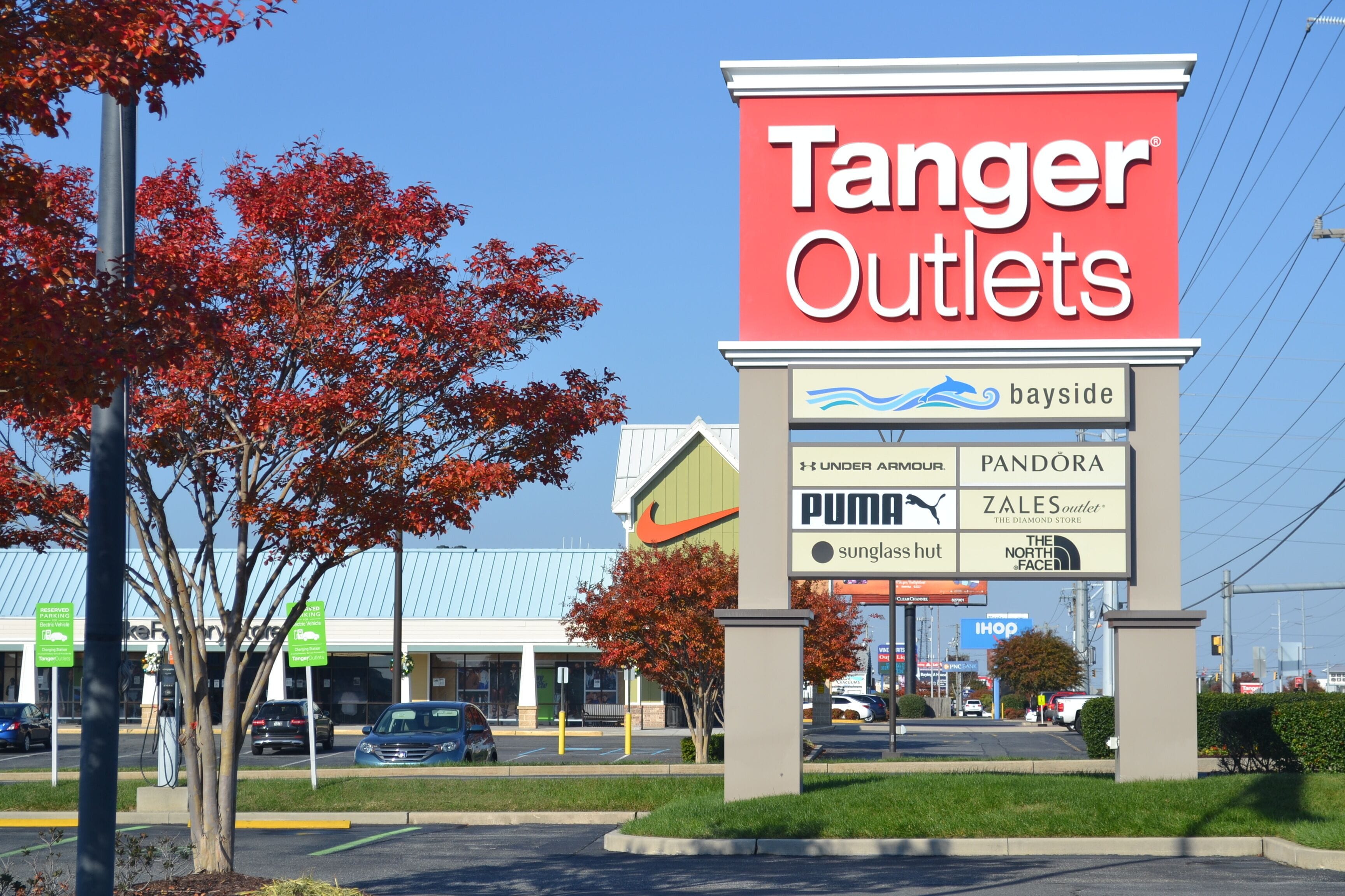 A Tanger Outlets sign with various store names like PUMA, ZALES, and SUNGLASS HUT.