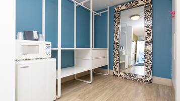 Une pièce avec un bureau blanc, un four à micro-ondes et un miroir à motifs.