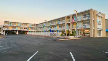 A multi-story hotel with a parking lot in front.