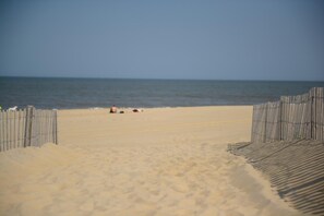 A sandy beach with a wooden fence leading to the water.