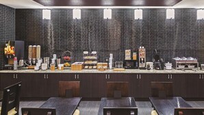 Een moderne keuken met donkere kastjes, een granieten aanrechtblad en diverse apparaten, waaronder een koffieapparaat, magnetron en broodrooster.