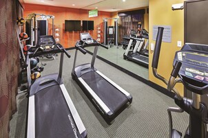 Un gimnasio con cintas de correr, máquinas de pesas y un espejo grande.