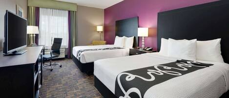 A hotel room with two beds, a desk with a TV, and a chair.