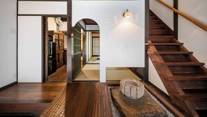 Een houten trap met een leuning, leidend naar een kamer met tatami vloeren en een traditioneel Japans interieur.