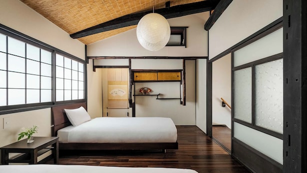 Een traditionele Japanse slaapkamer met tatami vloeren, een laag houten bed en schuifdeuren.