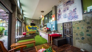 A modern interior with a wooden bench, a small table with a book and flowers, and a counter with various items. - The Chilli Bangkok (Bangkok)