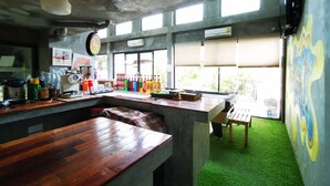 A bar area with a wooden counter, bottles, and a window with blinds. - The Chilli Bangkok (Bangkok)