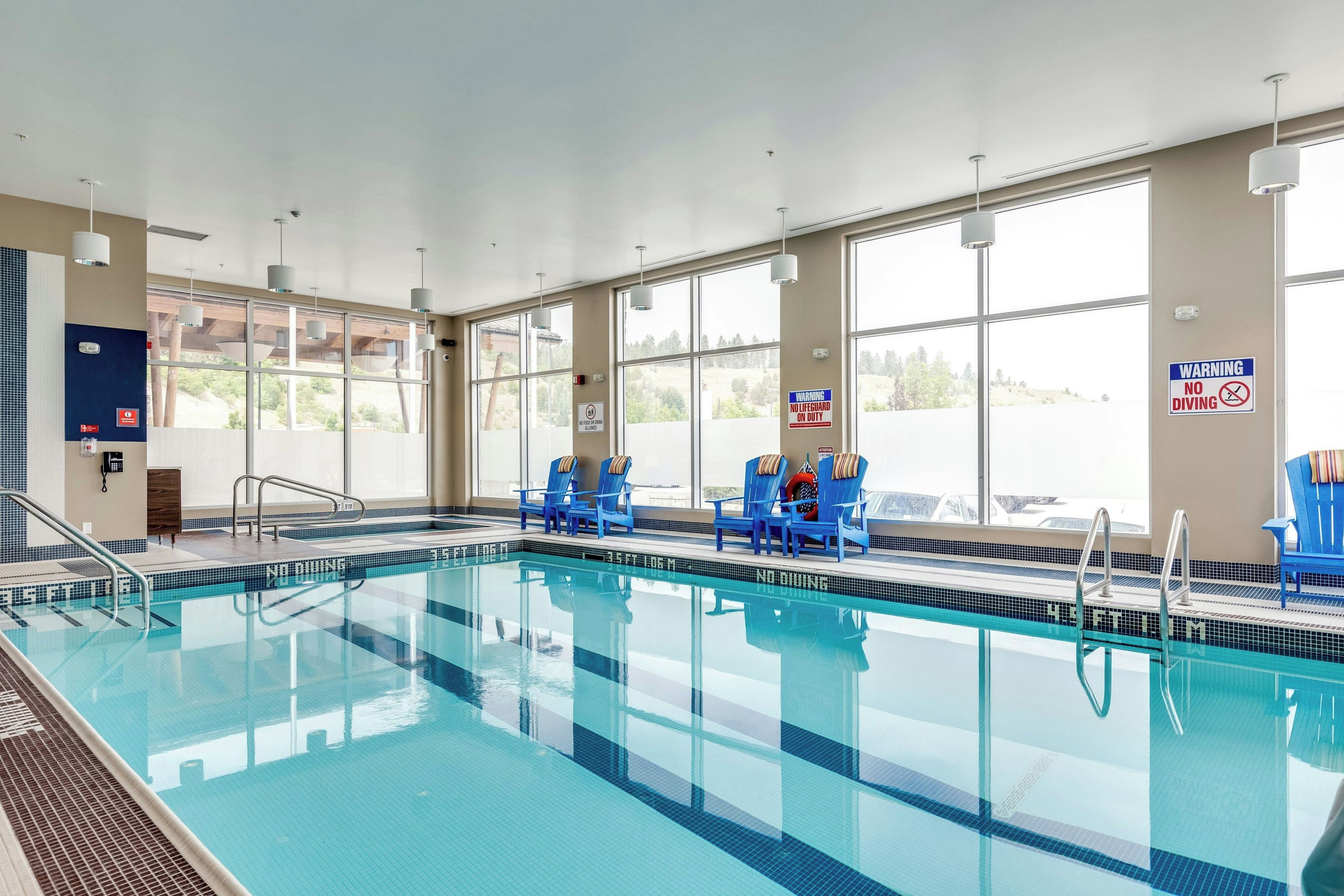 An indoor swimming pool with clear signage, including a 'No Diving' warning, and a 'No Lifeguard on Duty' sign.