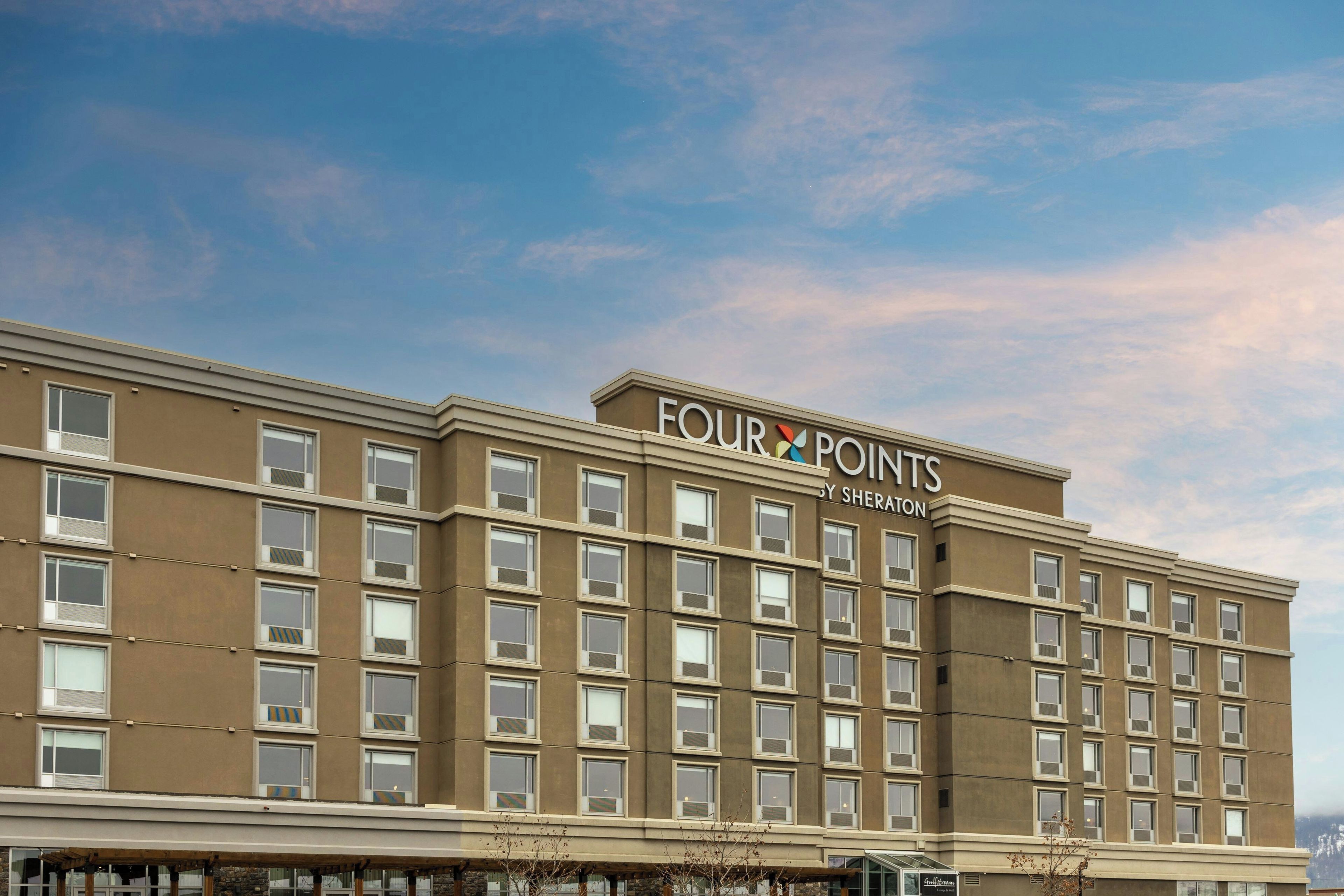 Un edificio de hotel de varios pisos con un letrero que dice 'FOUR POINTS BY SHERATON'.