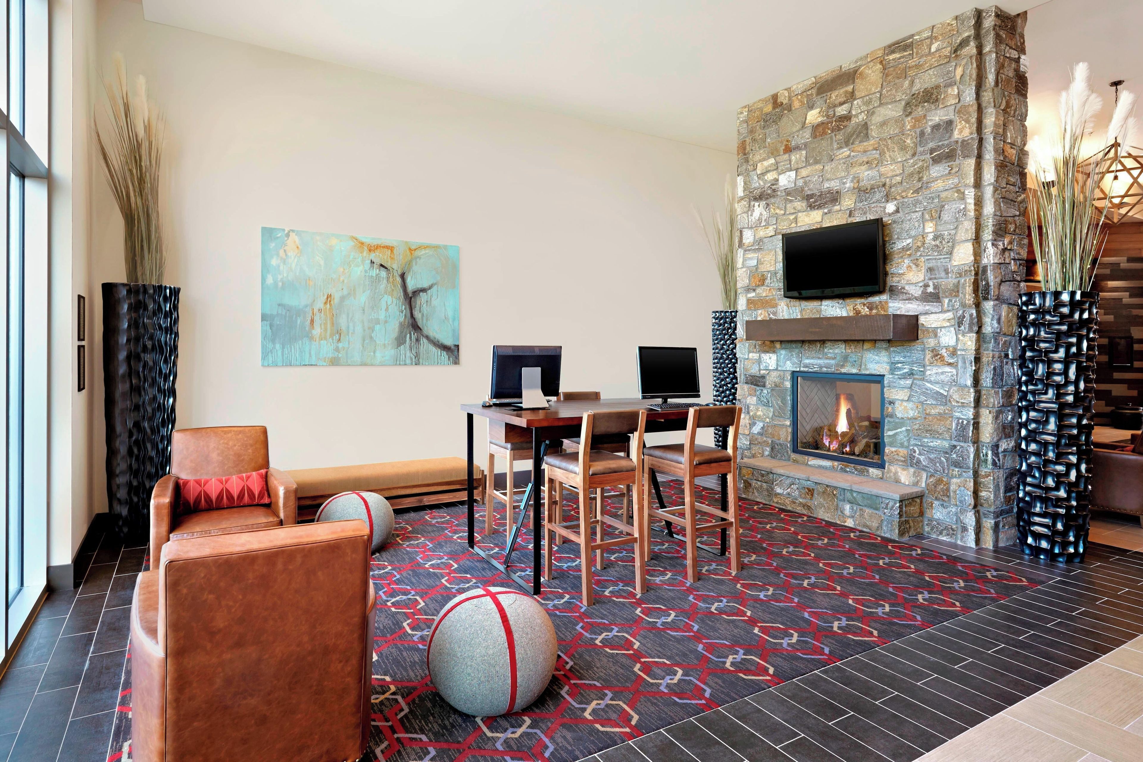 A modern living room with a stone fireplace, a flat-screen TV, and a dining area with a round table and chairs.