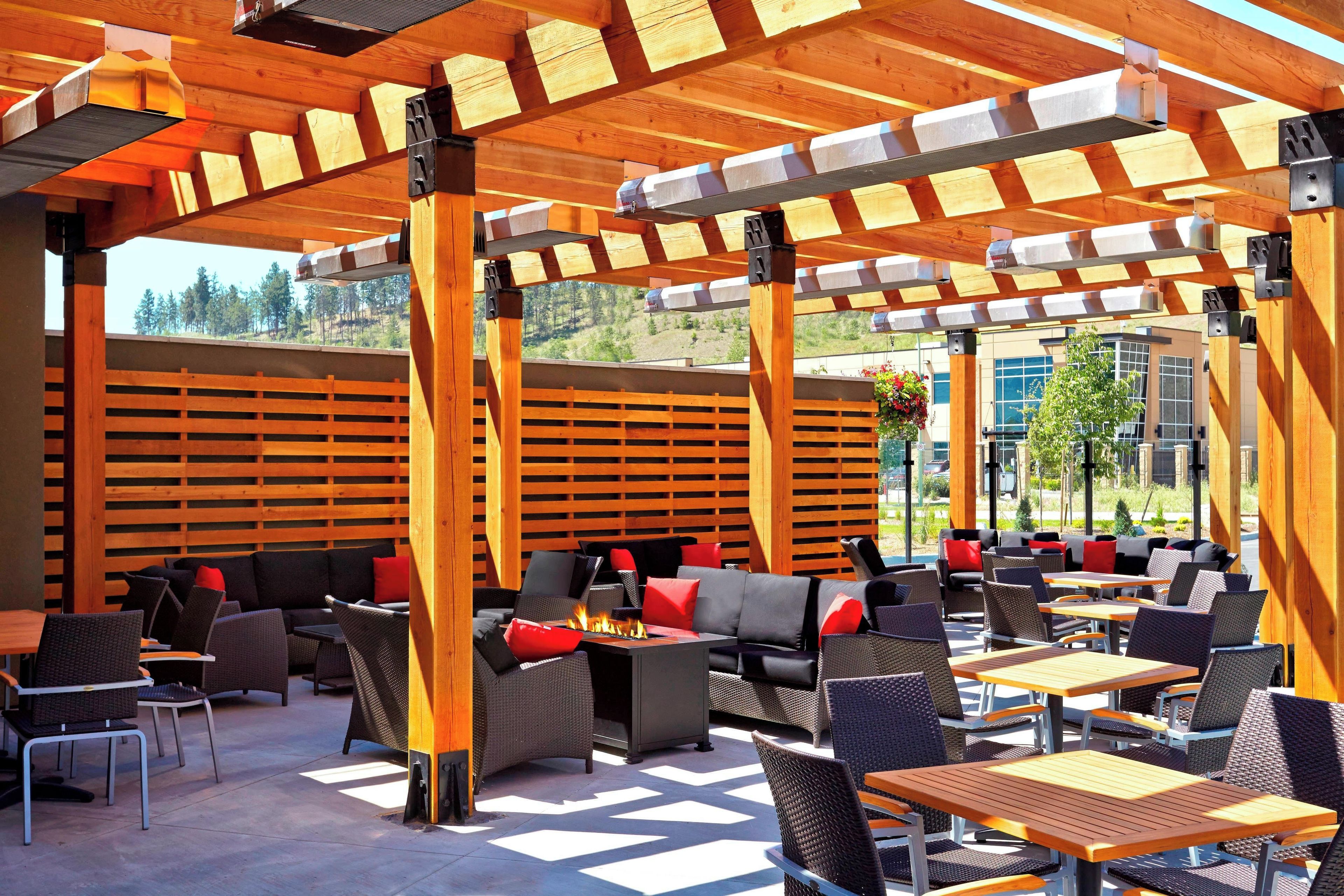Un espace extérieur aménagé en terrasse, avec des pergolas en bois, des coins salon et un foyer.