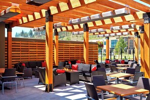 An outdoor patio area with wooden pergolas, seating arrangements, and a fire feature.