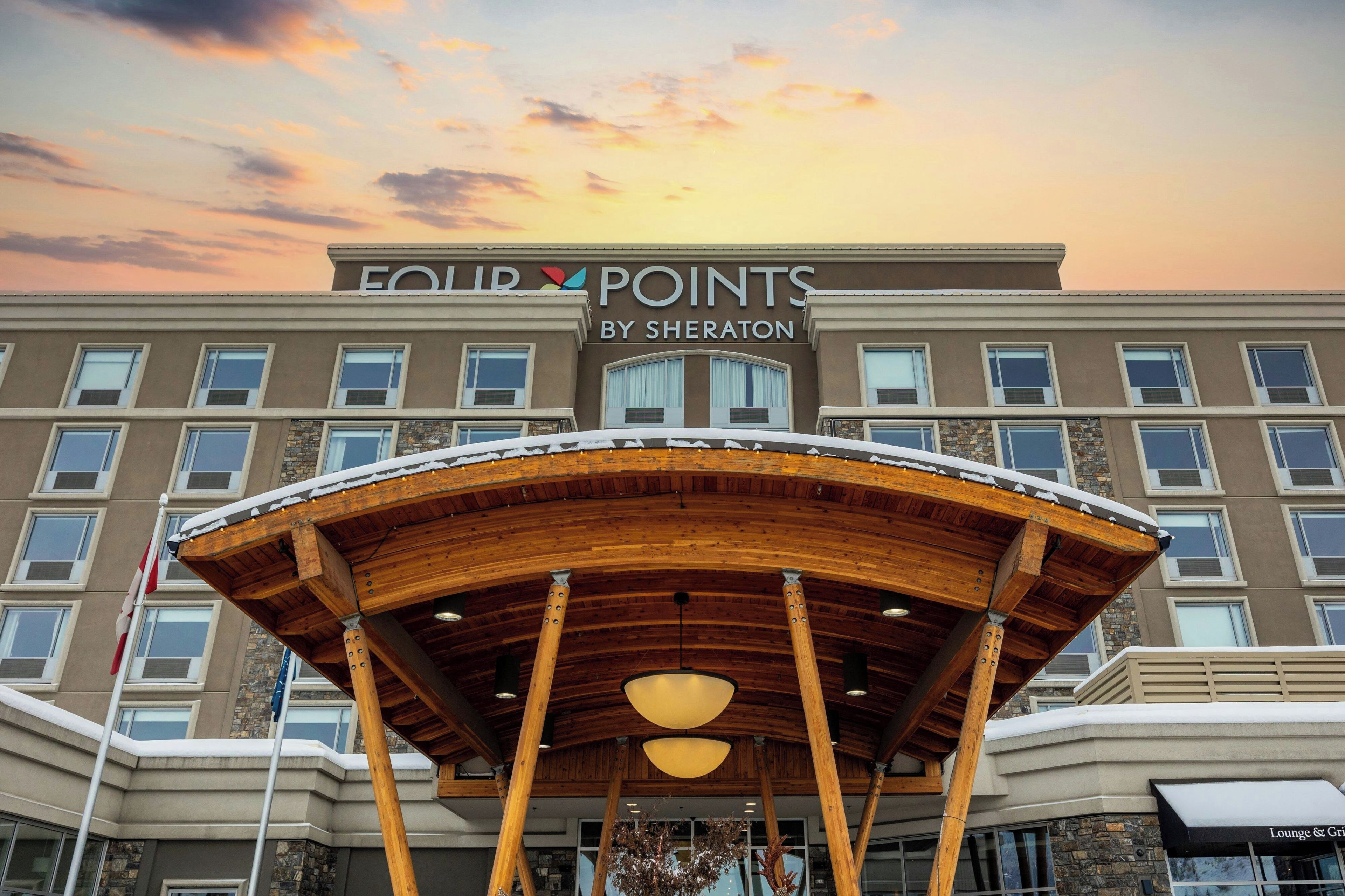 L’entrée d’un hôtel, dotée d’un espace extérieur abrité, de nombreuses fenêtres et d’une enseigne indiquant « FOUR POINTS BY SHERATON ».