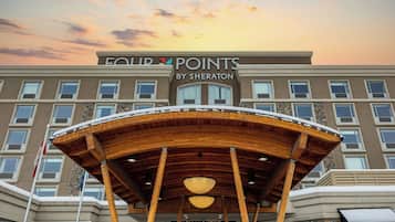 A hotel entrance with a covered outdoor area, multiple windows, and a sign reading 'FOUR POINTS BY SHERATON'.