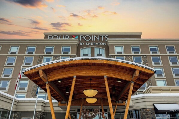 Entrada de un hotel con un área exterior techada, varias ventanas y un cartel que dice 'FOUR POINTS BY SHERATON'.