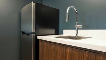 A kitchen with a stainless steel refrigerator, a white countertop, and a modern faucet.