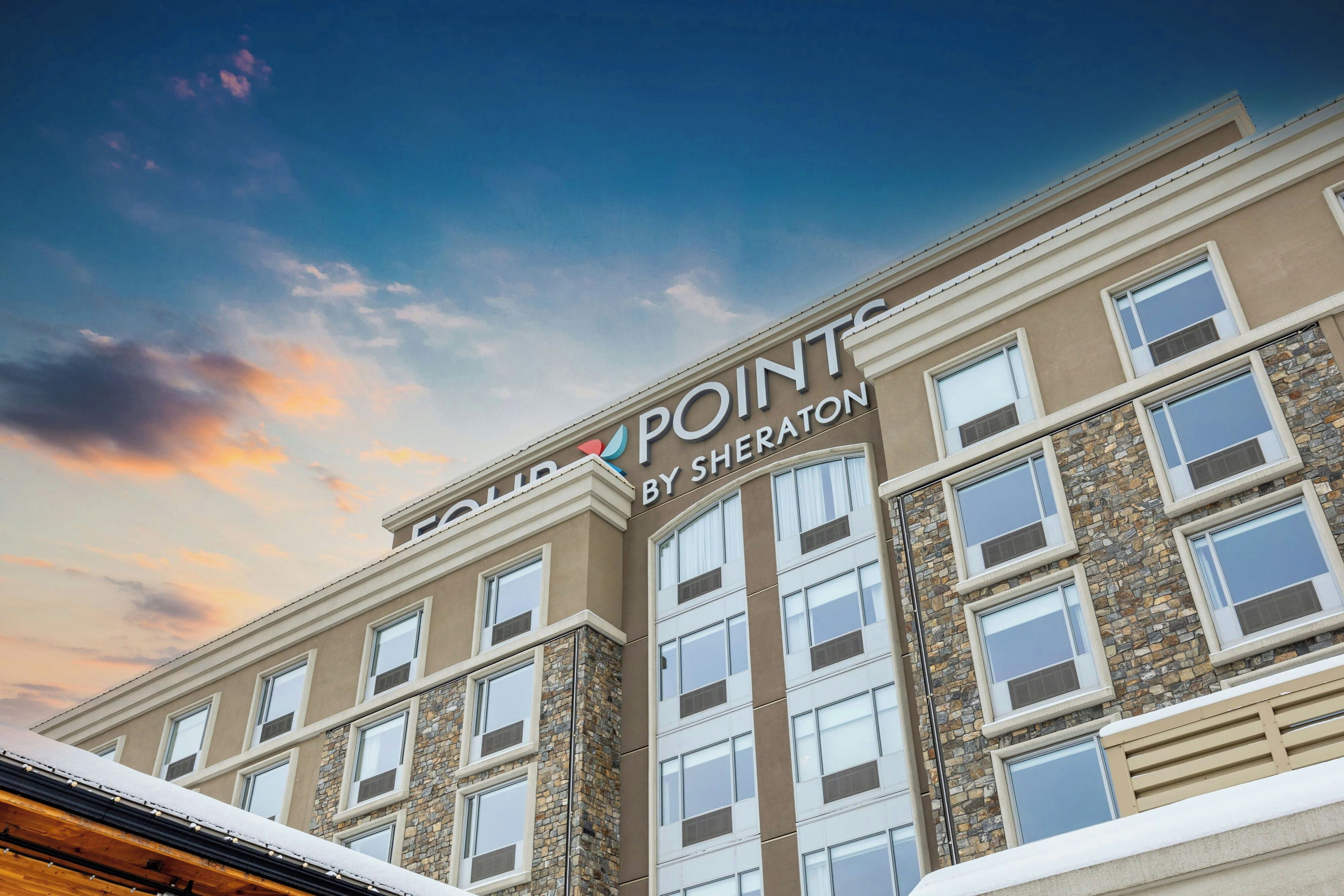 A building with the sign 'COLLINS POINTE BY SHERATON' indicating a hotel or property name.