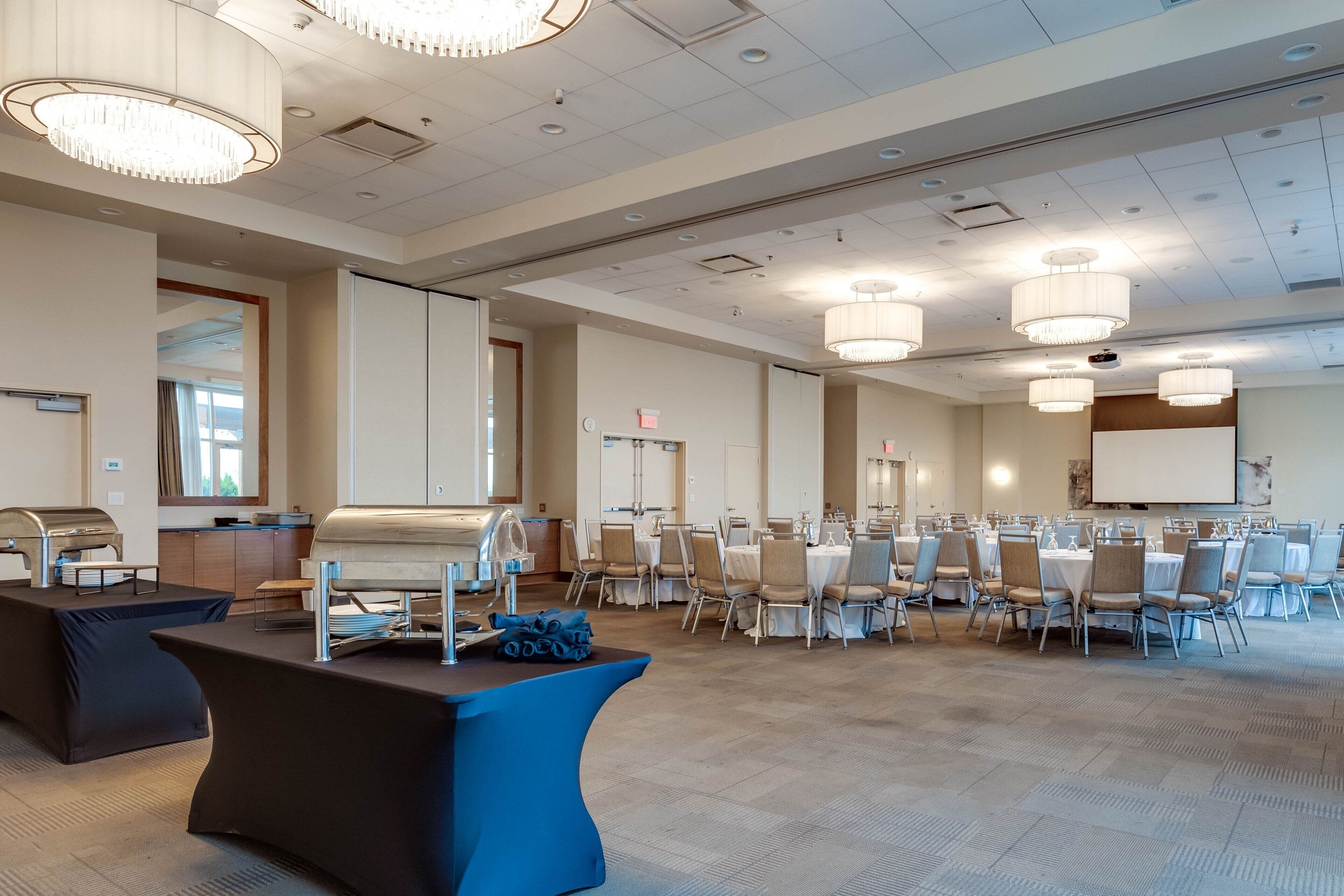 A spacious conference room with a long table, multiple chairs, and a projector screen.