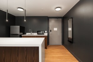 Une cuisine moderne avec un plan de travail blanc, des murs de couleur foncée et un revêtement de sol en bois.