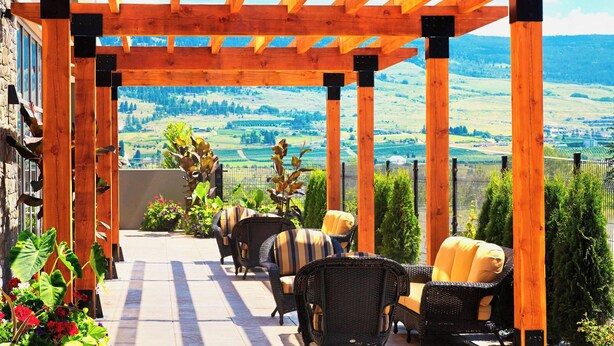 Un patio cubierto con mobiliario de mimbre y vistas a un paisaje verde.