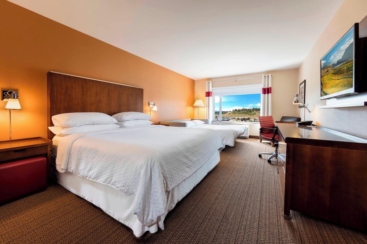 Quarto de hotel com uma cama grande, uma mesa e uma televisão.